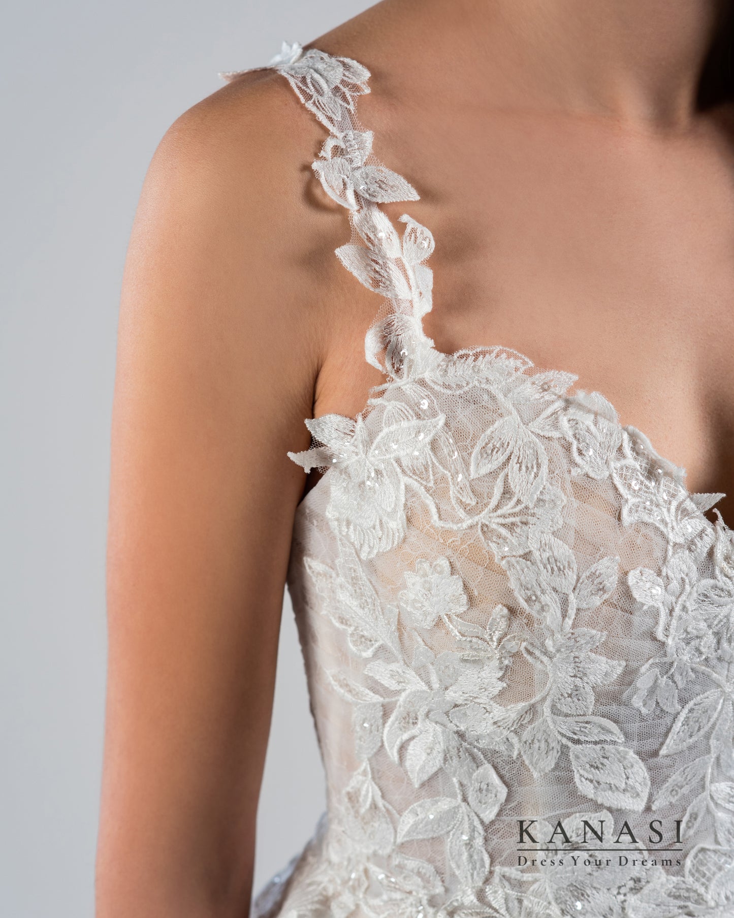 Detajl poročne obleke z naramnicami iz čipke.