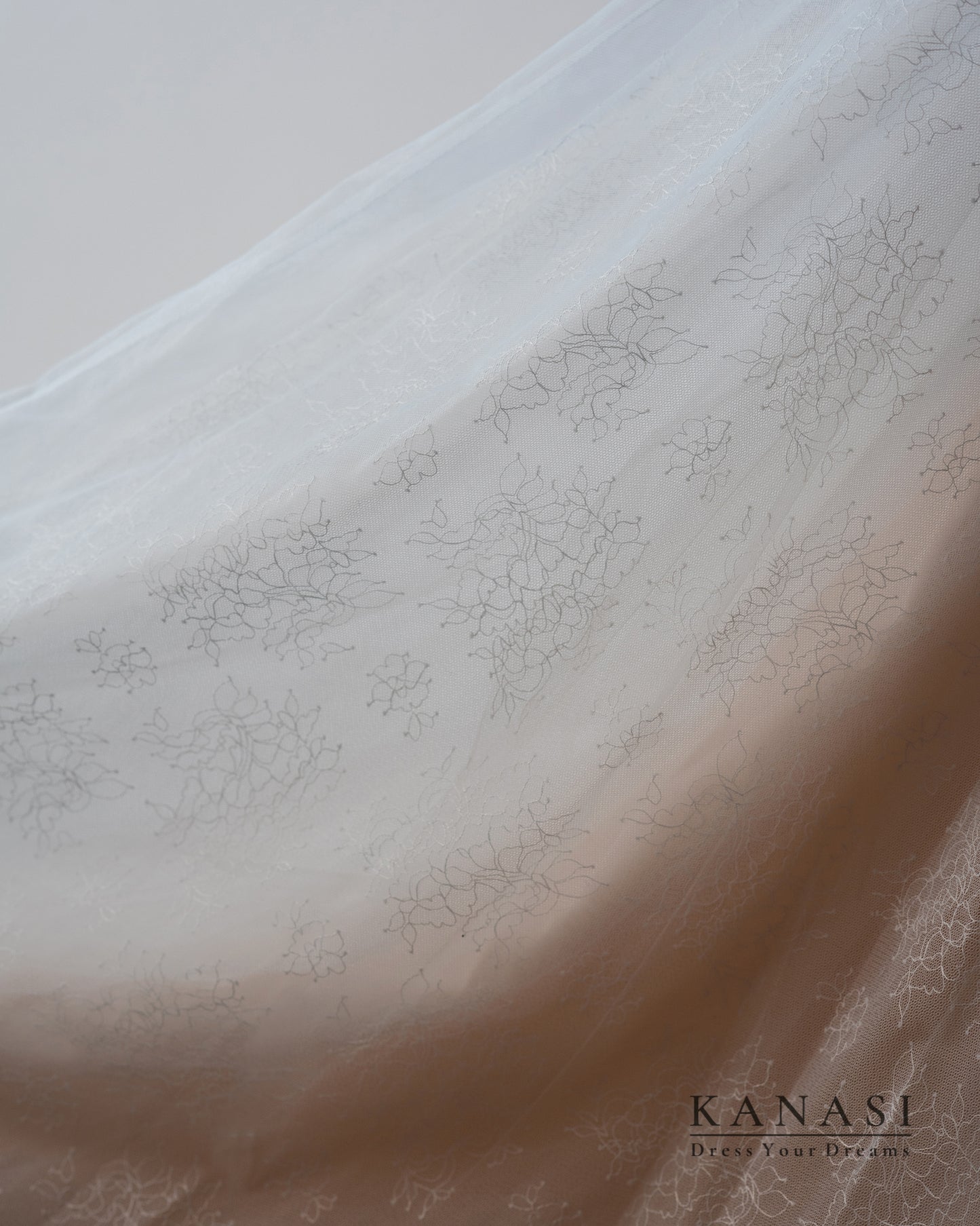 Detajl poročne obleke s svetlobo, ki prihaja iz ozadja.