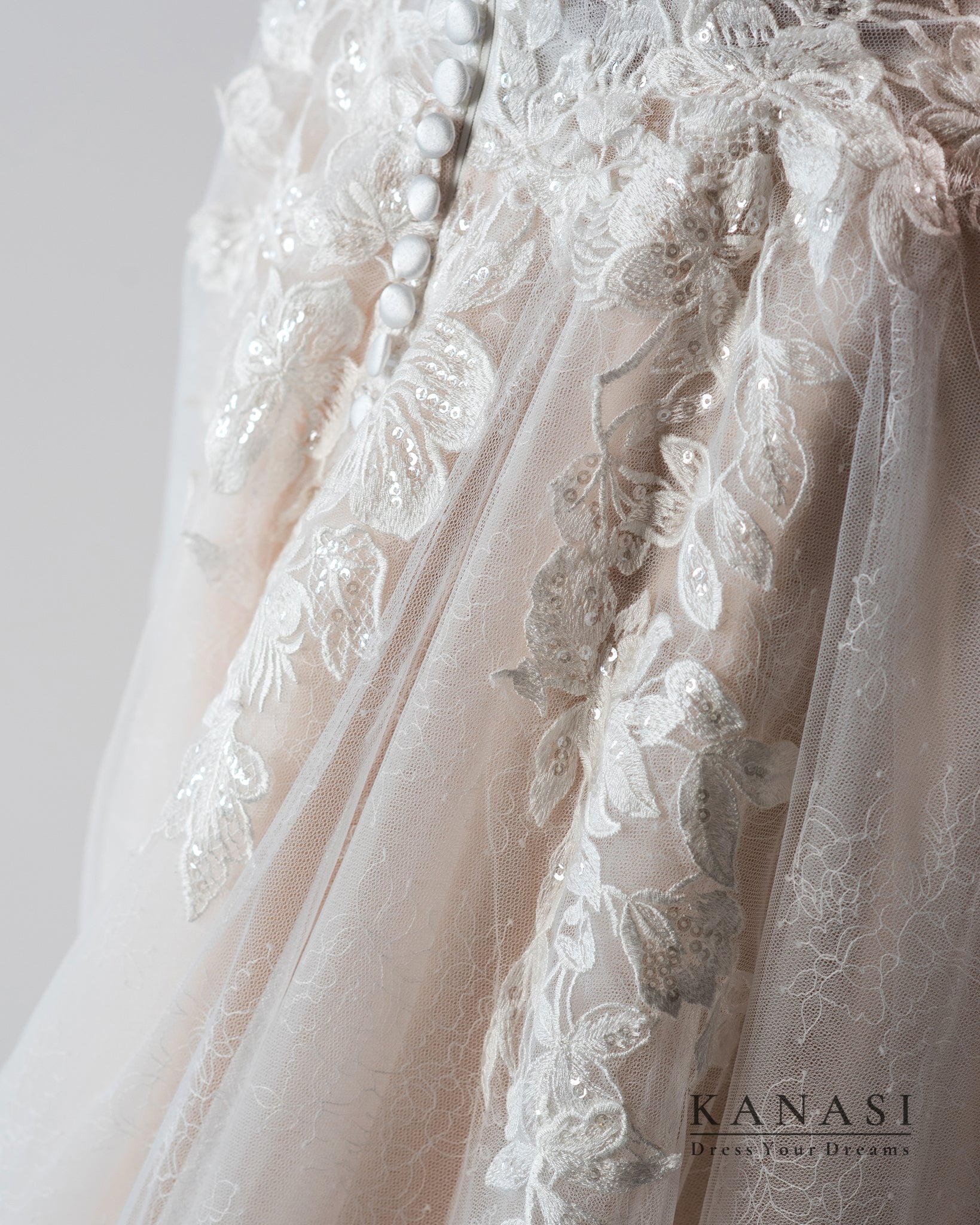 Poročna obleka od blizu s čiško in belimi gumbi.