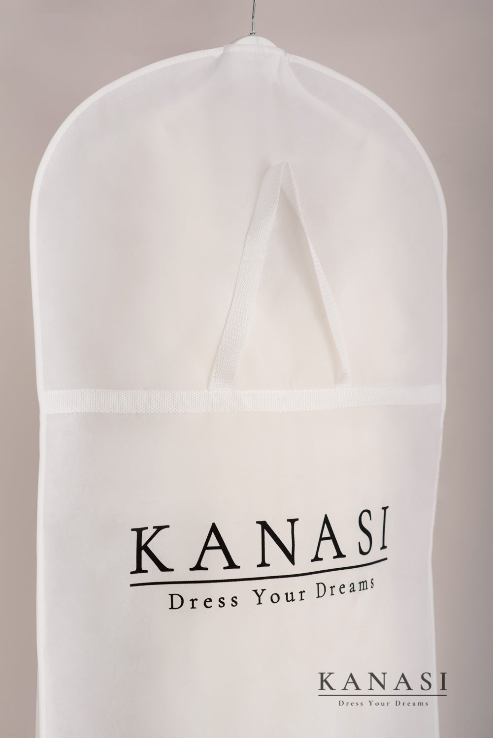 Bližnji posnetek zaščitne prevleke za poročno obleko – detajl ročaja in logotipa Kanasi na beli tkanini.
